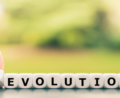 Evolution instead of revolution. Hand turns a dice and changes the word "revolution" to "evolution".