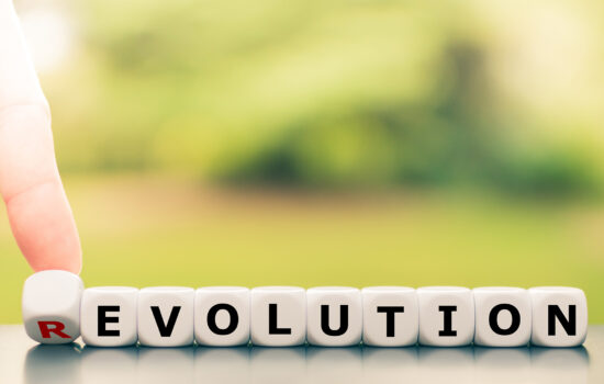 Evolution instead of revolution. Hand turns a dice and changes the word "revolution" to "evolution".